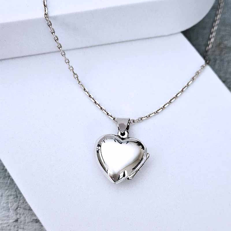 Silver heart-shaped locket on a chain against a white background