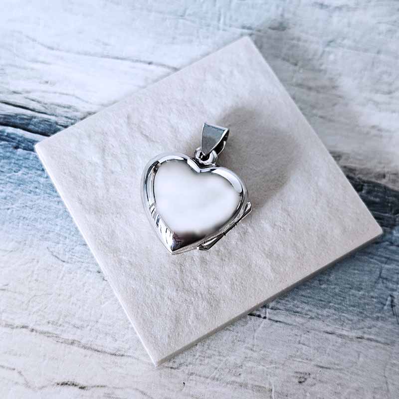 Silver heart-shaped pendant on a white stone surface