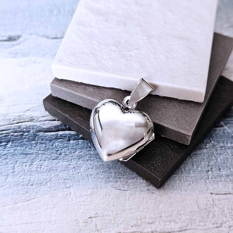 Silver heart-shaped pendant on a textured surface
