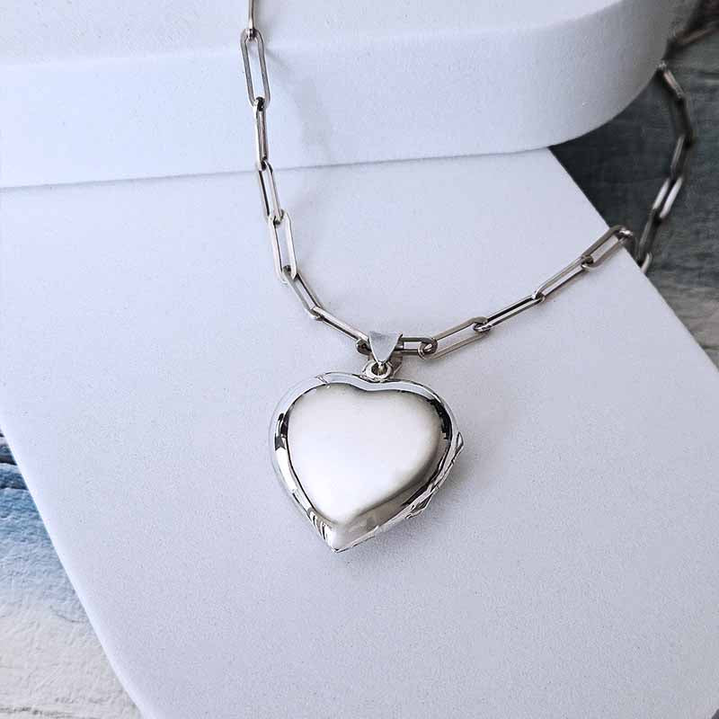 Silver heart-shaped locket on a chain against a white background