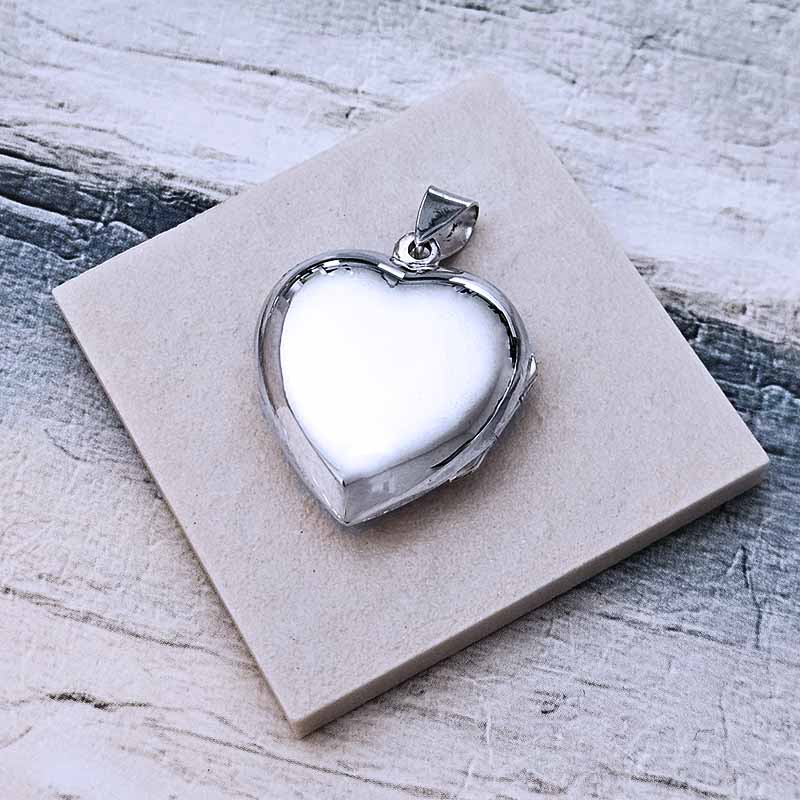Heart-shaped silver pendant on a textured stone surface