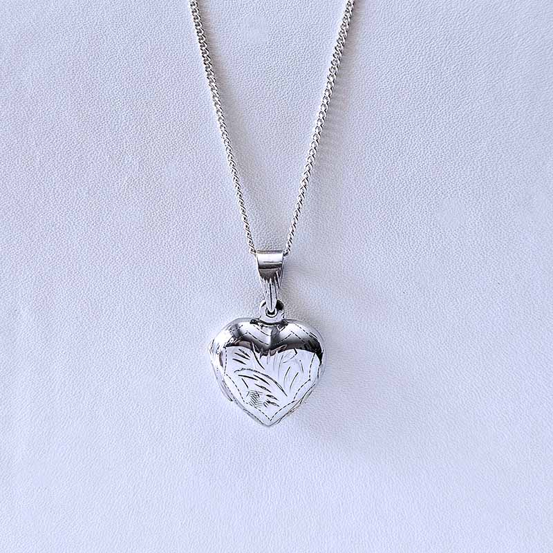 Silver heart-shaped pendant on a chain against a light gray background