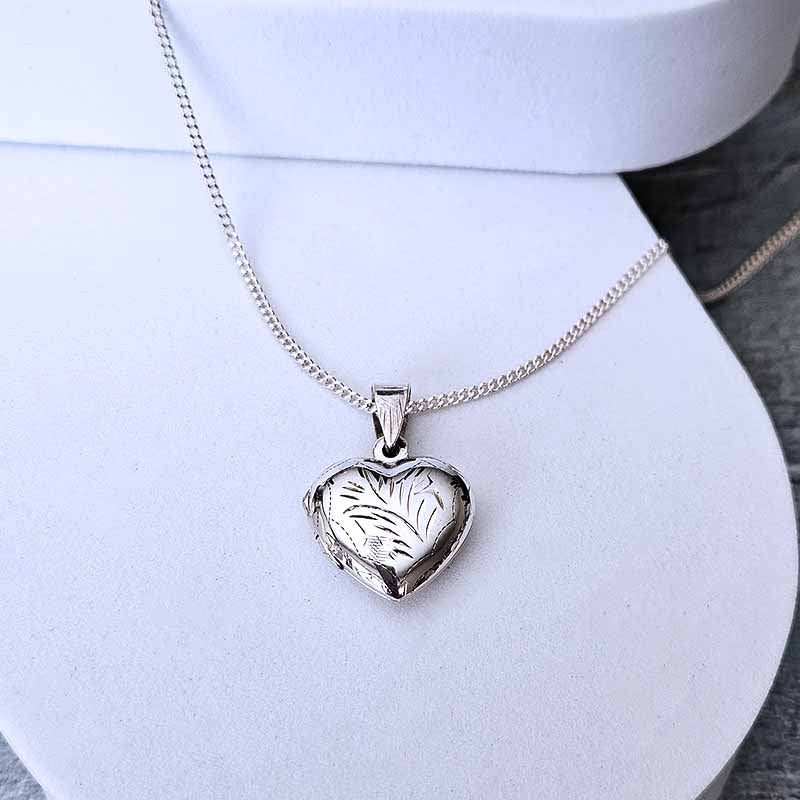 Silver heart-shaped locket on a white stand
