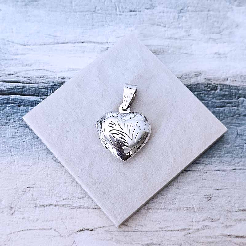 Silver heart-shaped pendant on a white card with a textured gray background