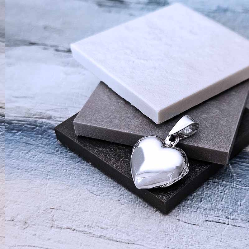 Silver heart-shaped pendant on a textured surface
