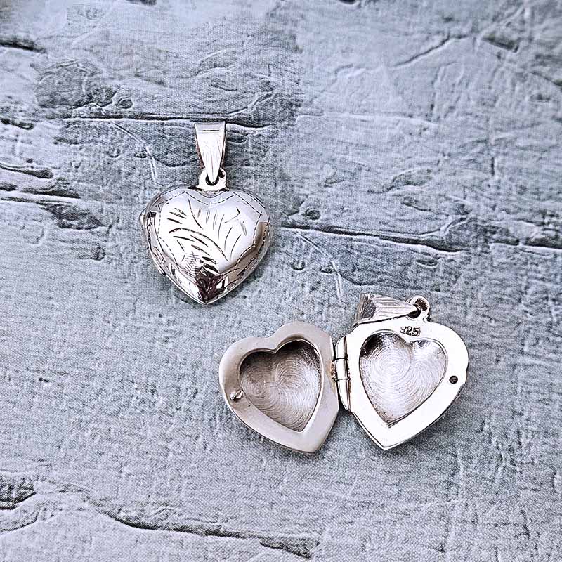 Silver heart-shaped locket on a textured gray surface