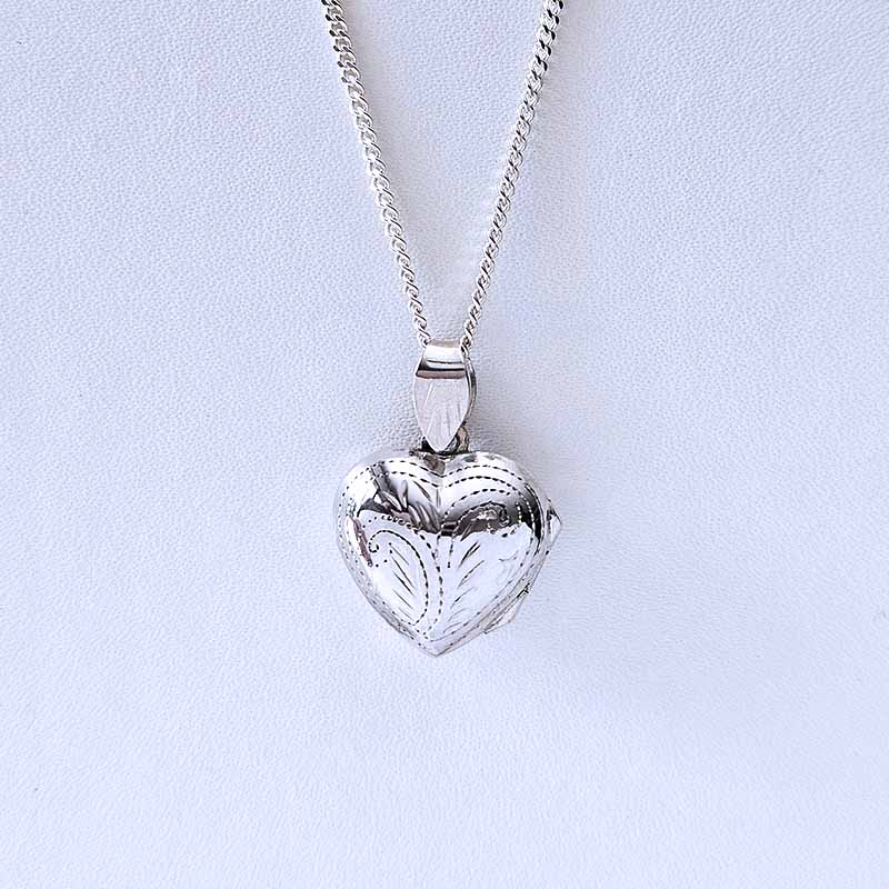Silver heart-shaped pendant on a chain against a light blue background