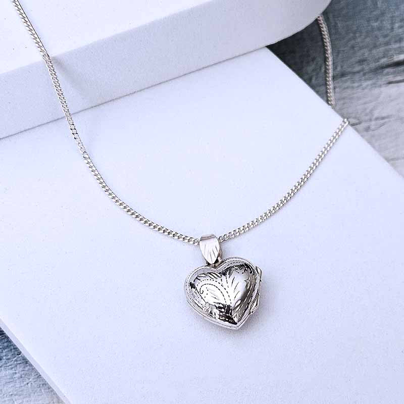 Silver heart-shaped locket necklace on a white surface