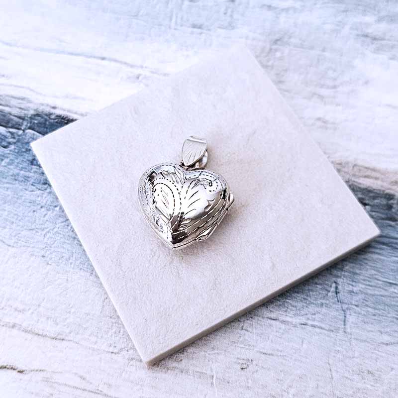 Silver heart-shaped locket on a white marble surface