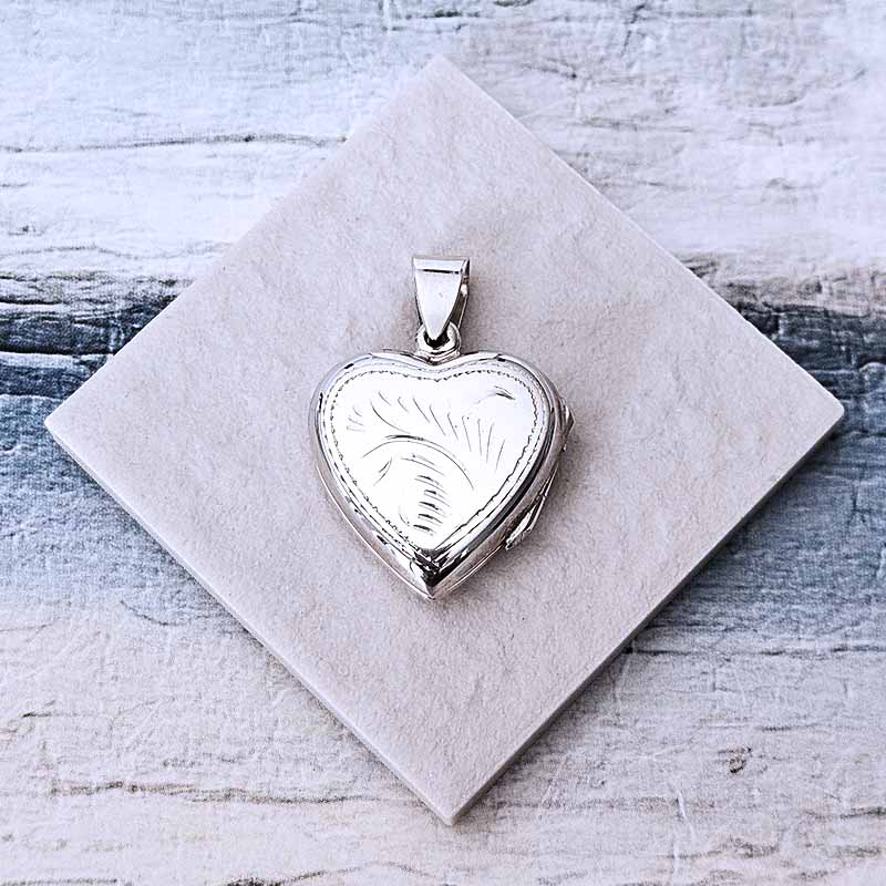Silver heart-shaped locket on a textured white card