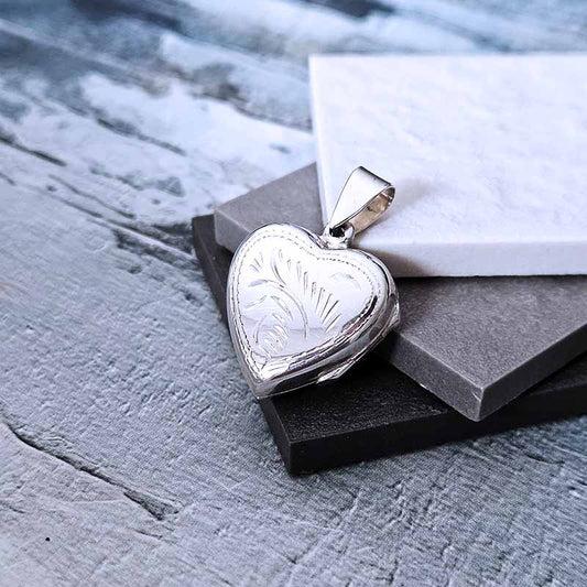 Heart-shaped silver locket on a textured surface with a marble background