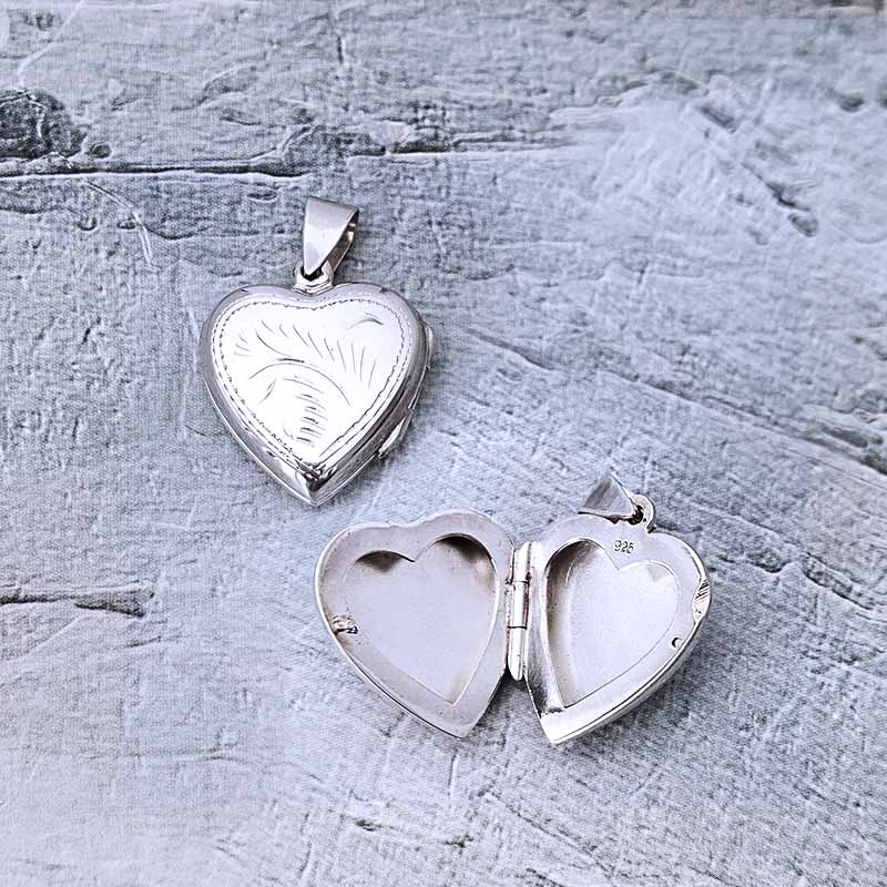 Silver heart-shaped locket on a textured gray surface