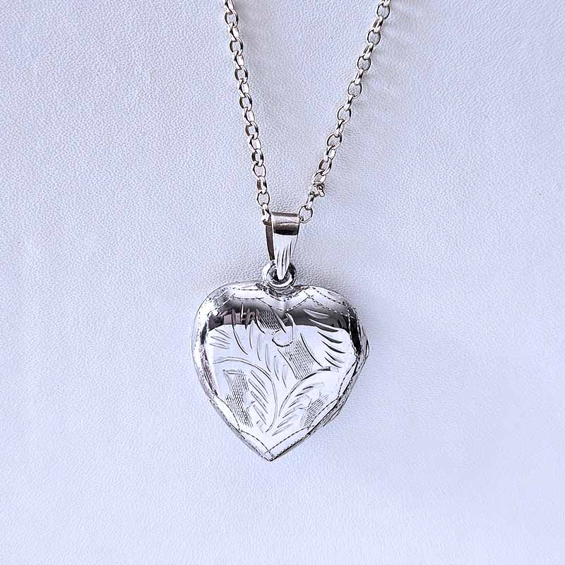 Silver heart-shaped pendant on a chain against a light gray background
