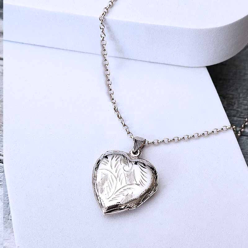 Silver heart-shaped locket necklace on a white surface