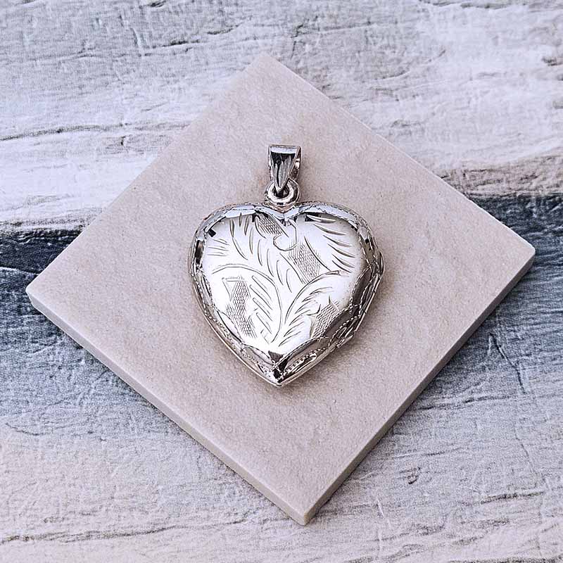 Silver heart-shaped locket on a textured stone surface