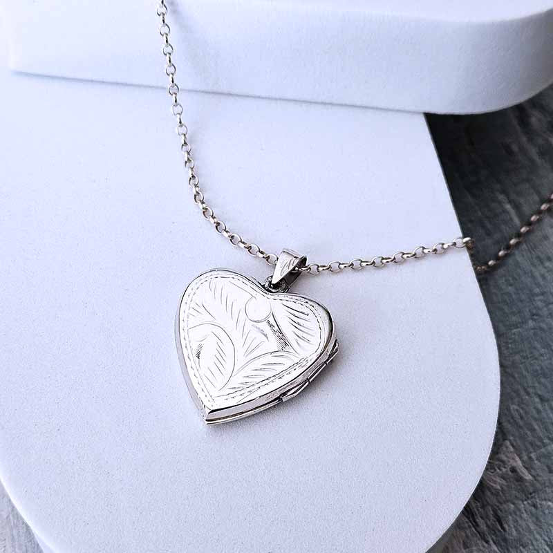 Silver heart-shaped locket on a chain against a white background