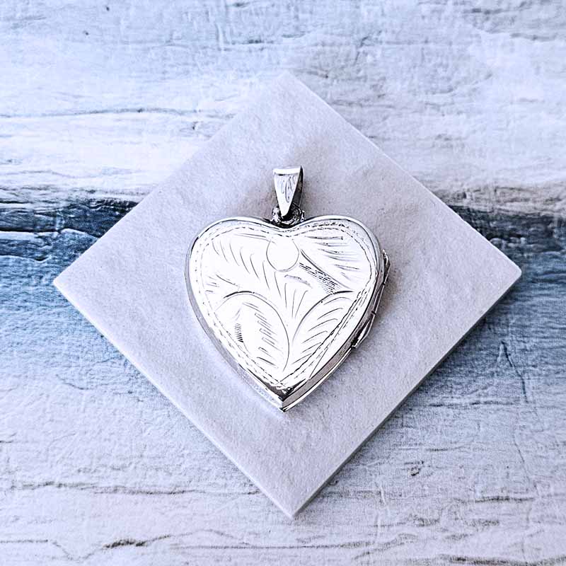 Silver heart-shaped locket on a white marble surface