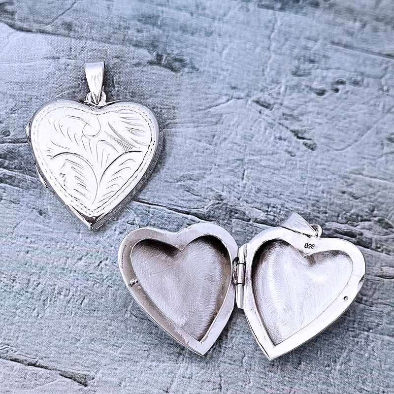 Silver heart-shaped locket on a textured gray surface