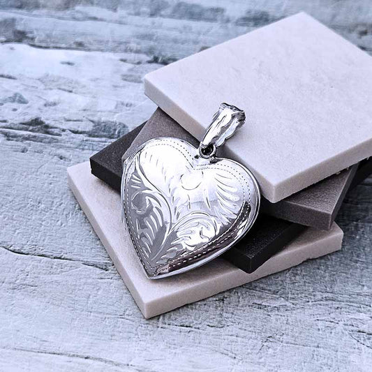 Silver heart-shaped pendant on a textured surface