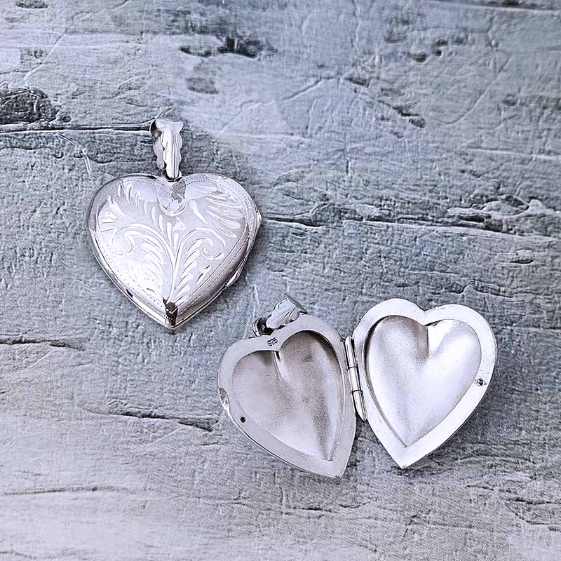 Silver heart-shaped locket on a textured gray surface