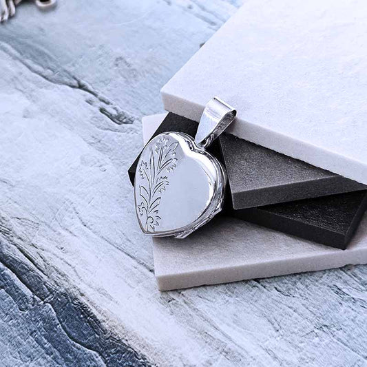 Silver locket with engraved design on a textured surface