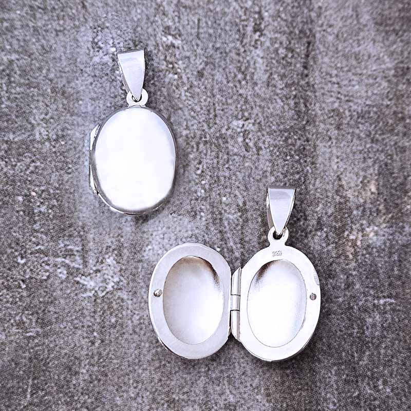 Two silver pendants on a textured gray surface