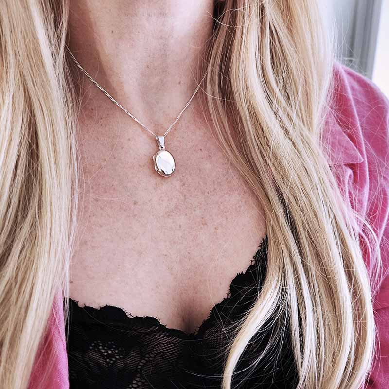 Close-up of a necklace with a pendant worn by a person with blonde hair.