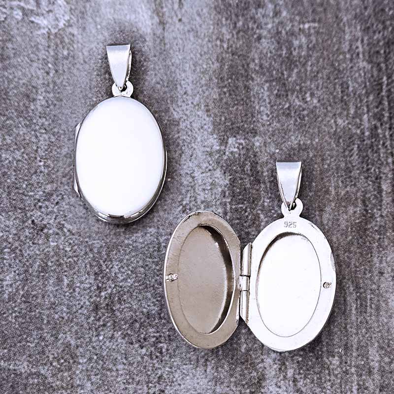 Two silver pendants on a textured gray surface