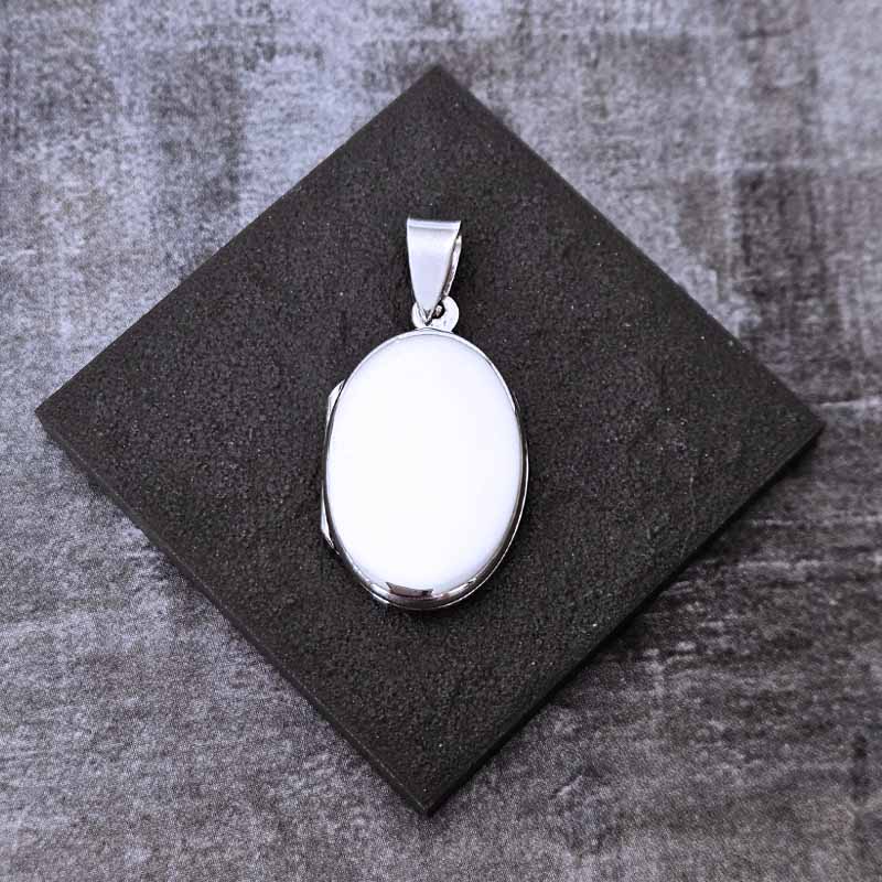 Silver locket pendant on a dark gray surface