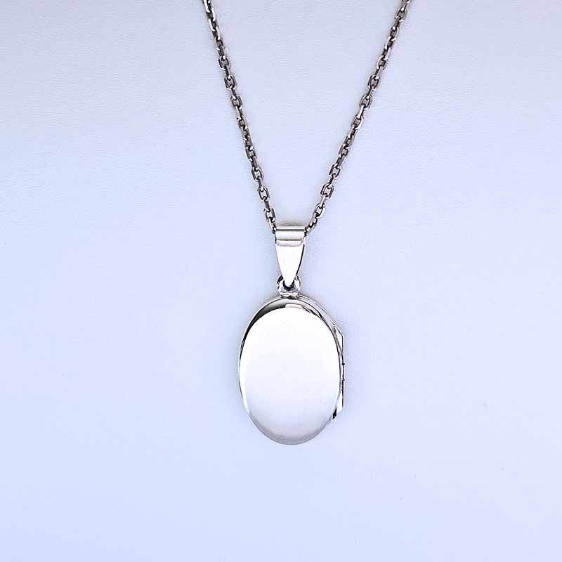 Silver locket on a chain against a light purple background
