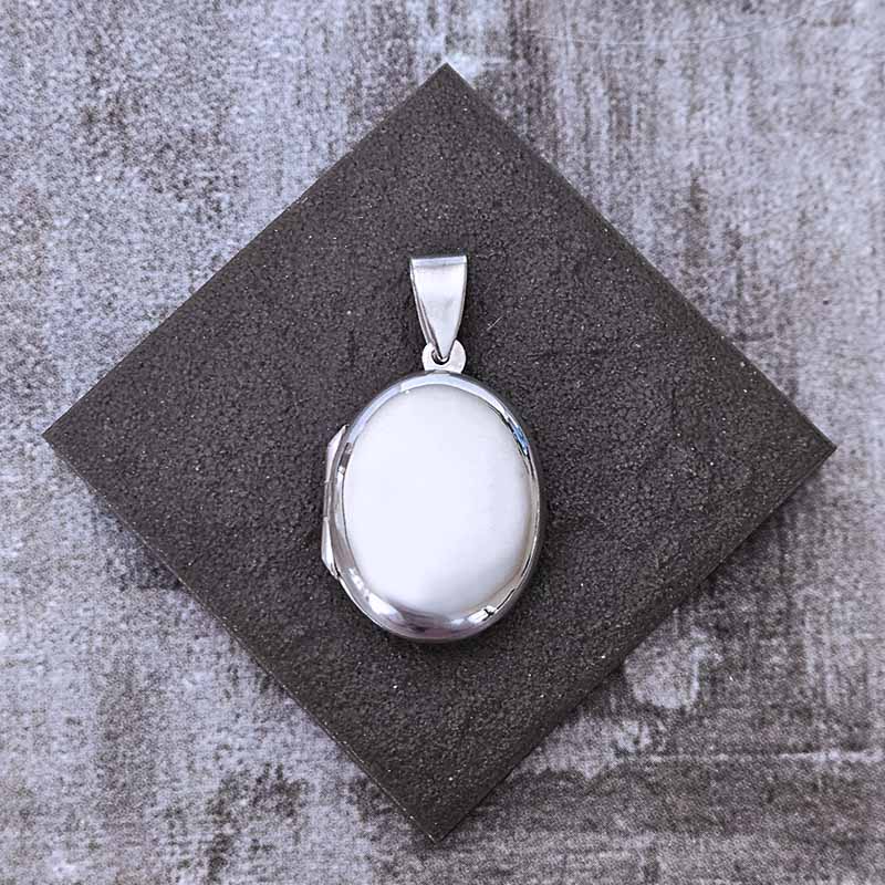 Silver oval locket pendant on a textured stone background