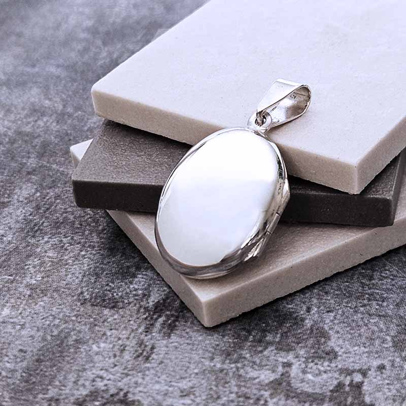 Silver locket pendant on a gray surface