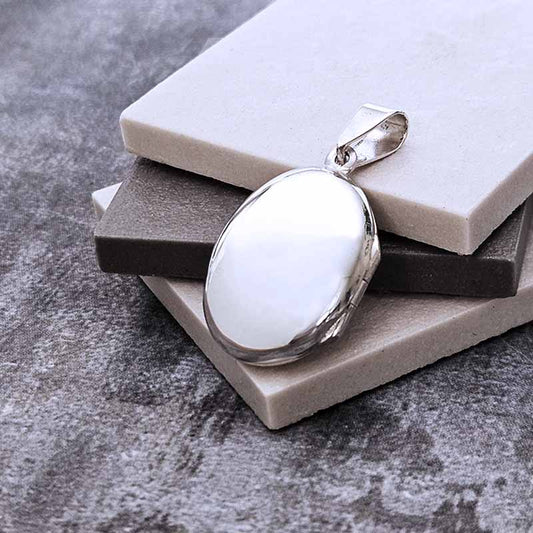 Silver locket pendant on a gray surface