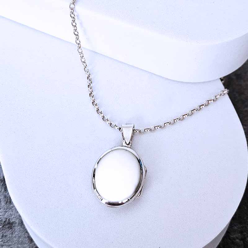 Silver necklace with a round pendant on a white background