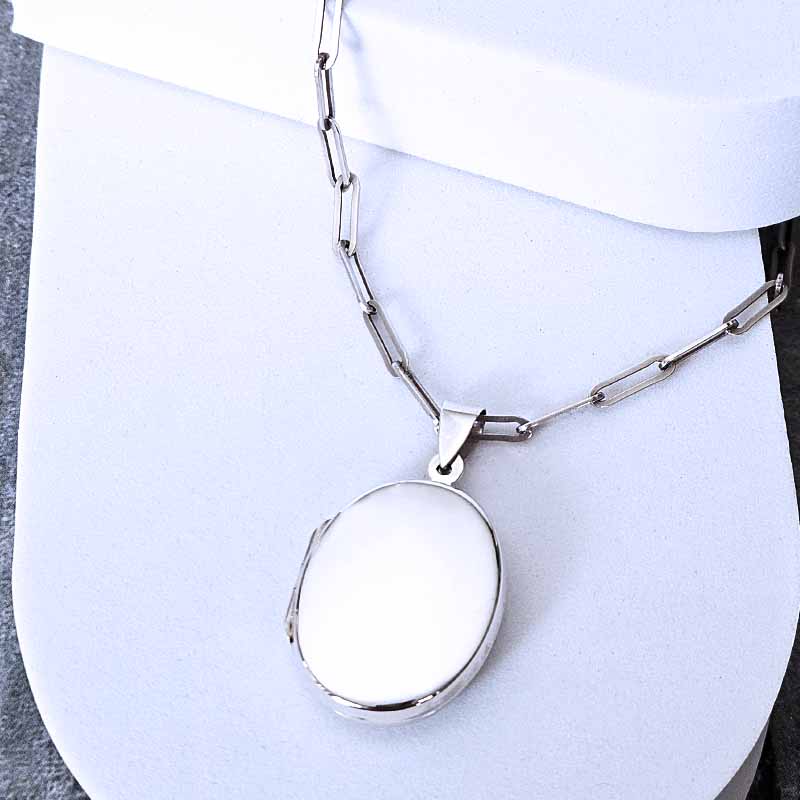 Silver necklace with a round pendant on a white background