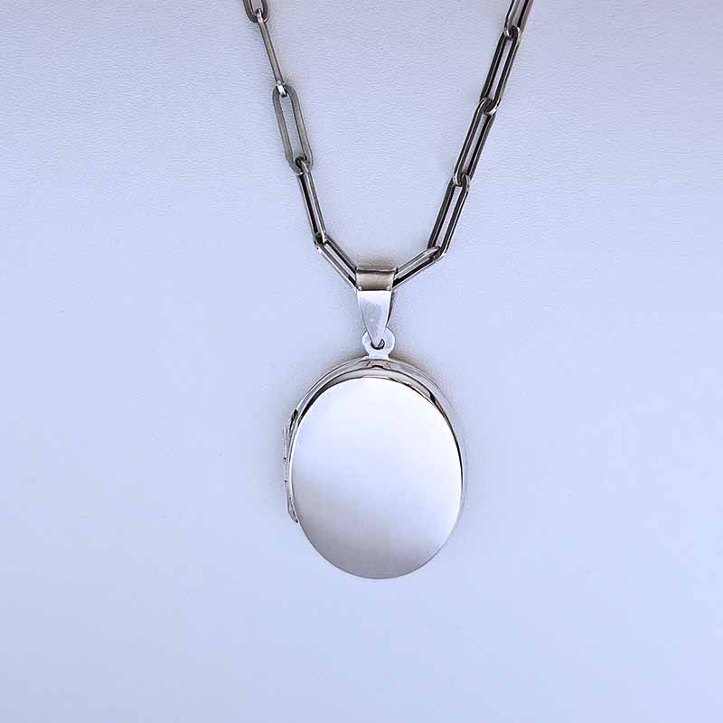 Silver locket necklace on a light purple background