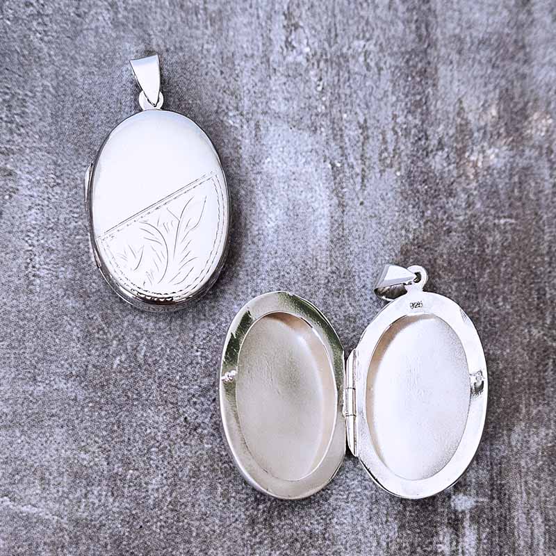 Silver locket with engraved design on a textured gray surface