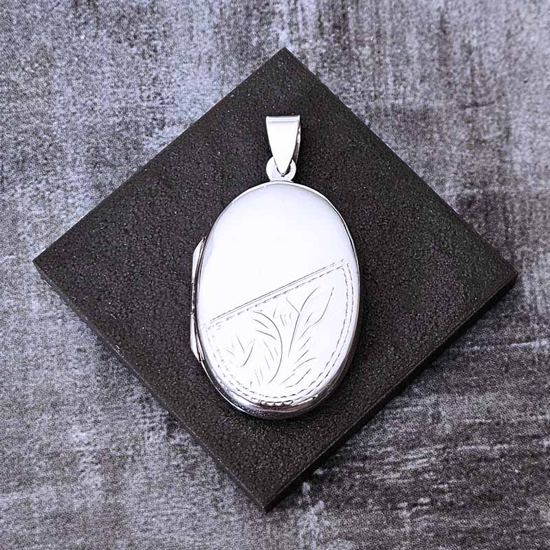 Silver locket with leaf design on a textured black surface