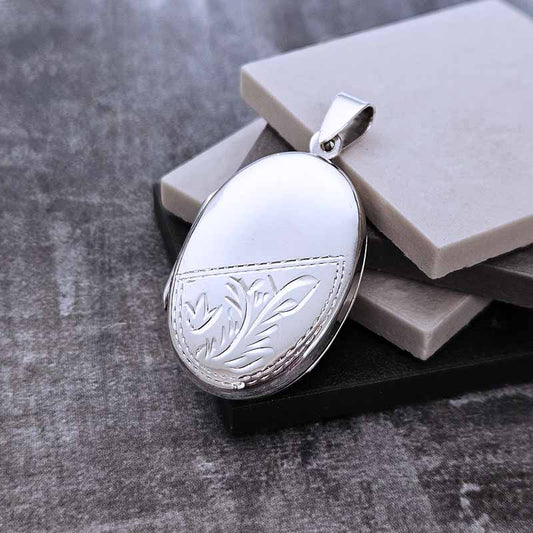 Silver locket with floral engraving on a textured surface