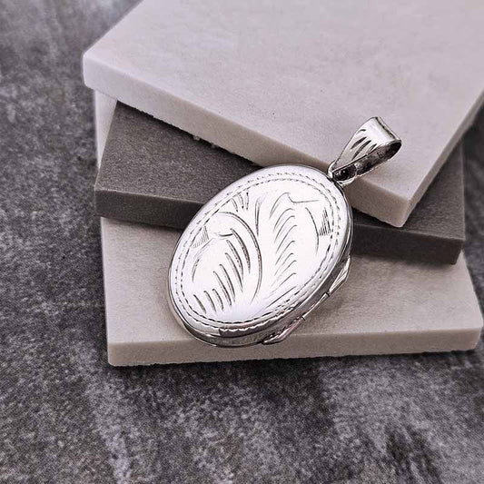 Silver locket with leaf design on a gray stone surface