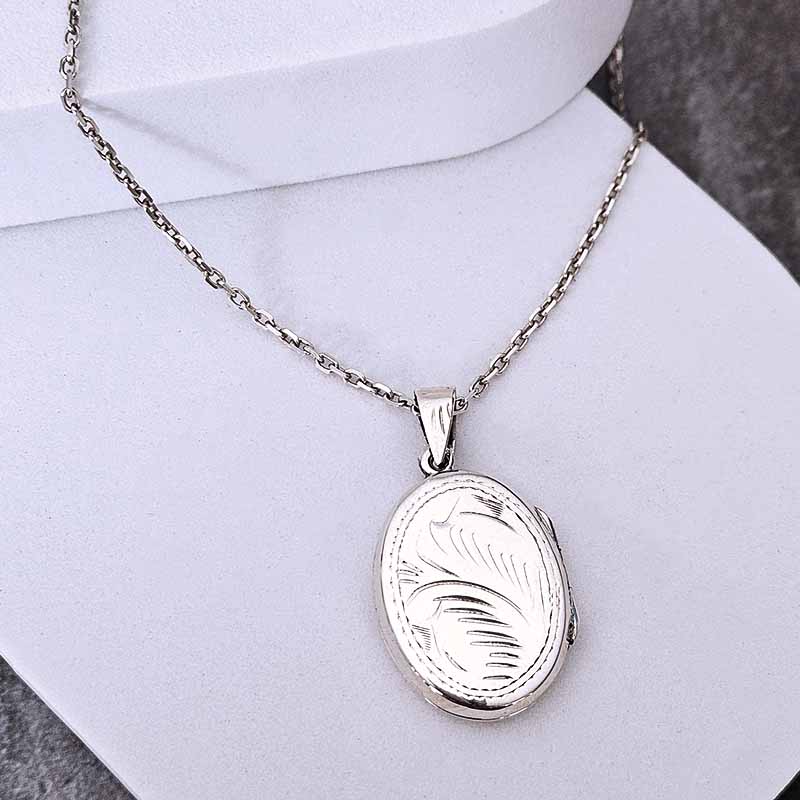 Silver locket necklace on a mannequin with a plain background