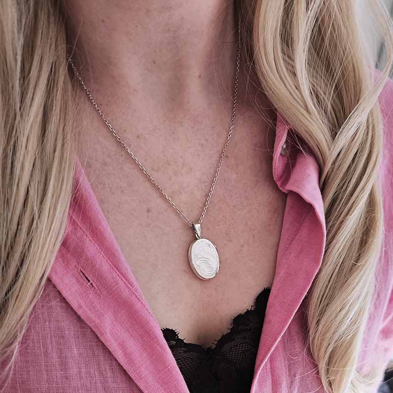Necklace with a pendant worn by a person with pink shirt and blonde hair.