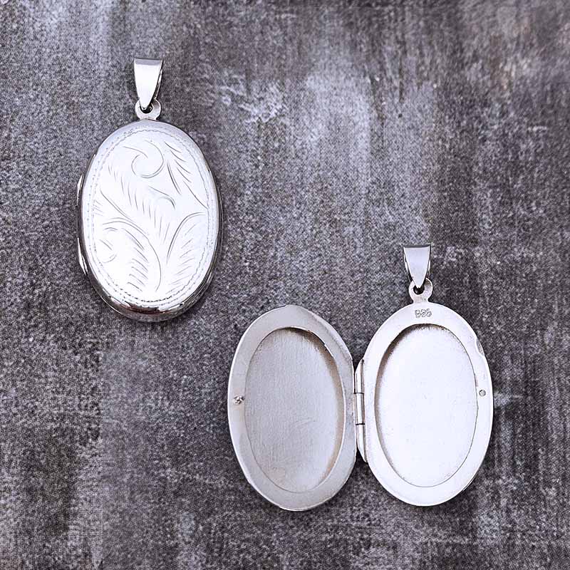 Two silver locket pendants on a textured gray background