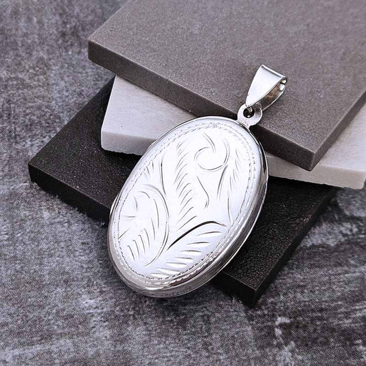 Silver locket with engraved design on a textured surface