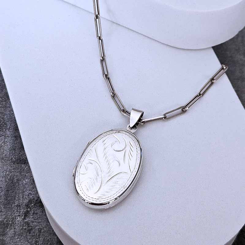 Silver necklace with an engraved pendant on a white surface