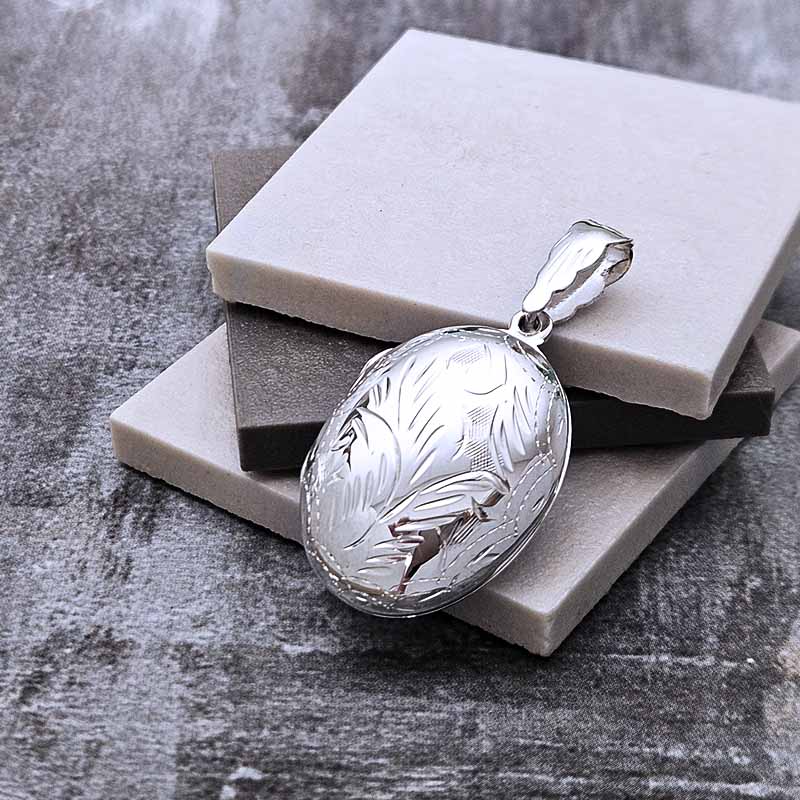 Silver pendant with engraved design on a stone surface