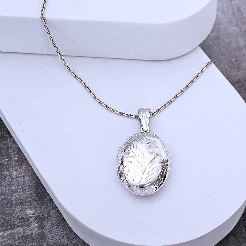 Silver necklace with a leaf-shaped pendant on a white surface