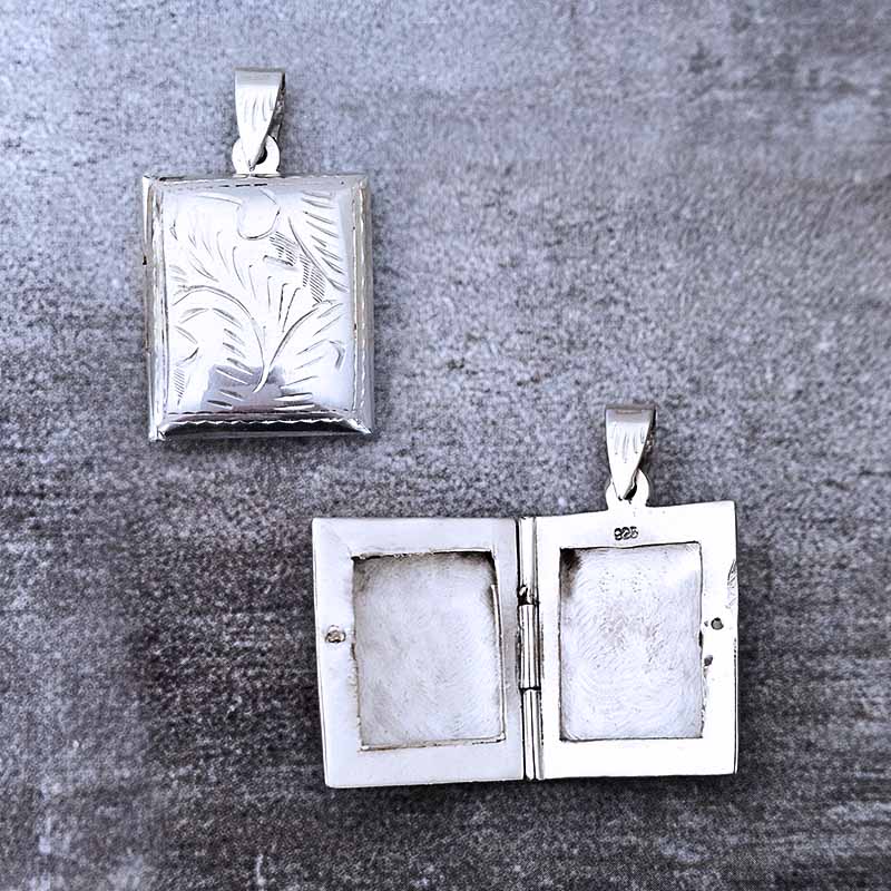 Two silver photo pendants on a textured gray background