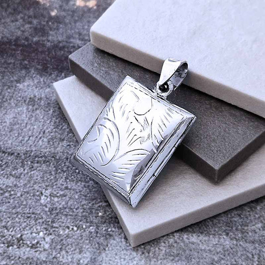 Silver pendant with leaf pattern on a stone surface