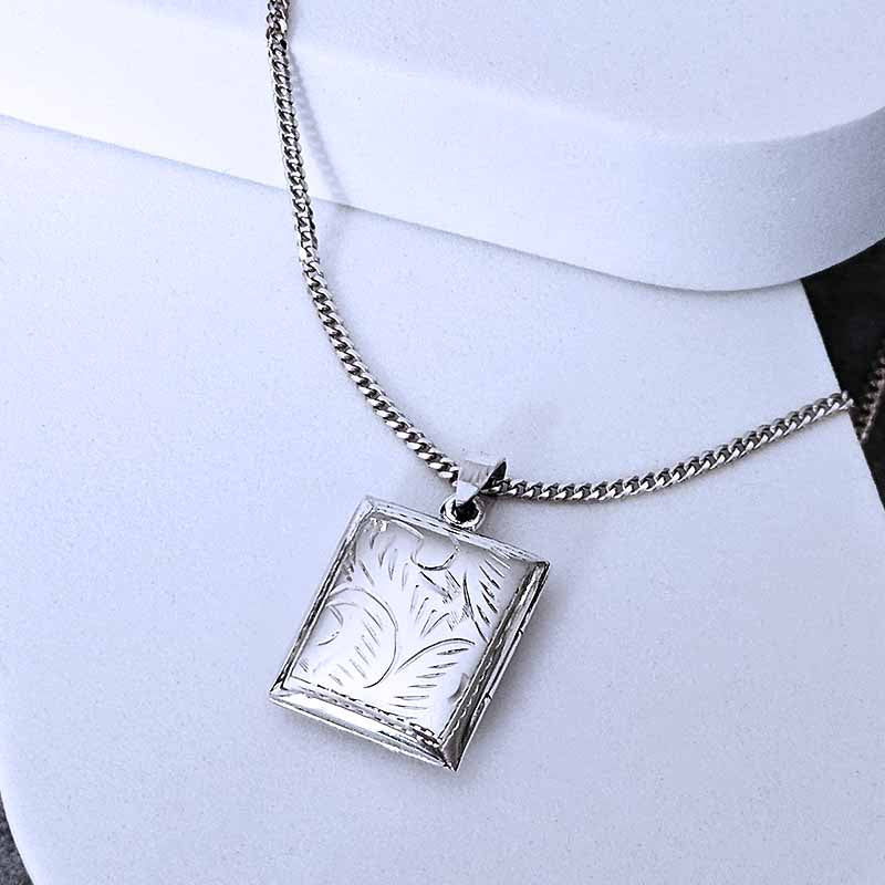 Silver necklace with a square pendant on a white background